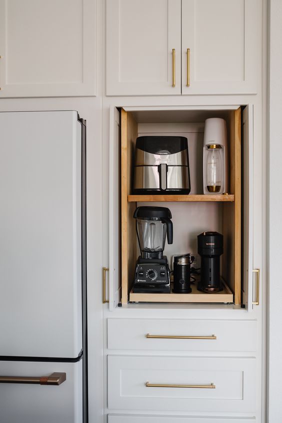 In cabinet storage shelves with various small kitchen appliances stored.